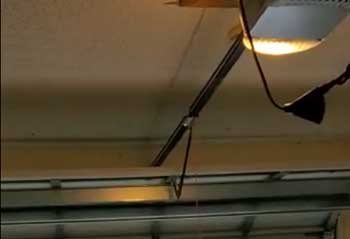 Technician working on electric garage door opener replacement inside a garage in El Cajon, CA.
